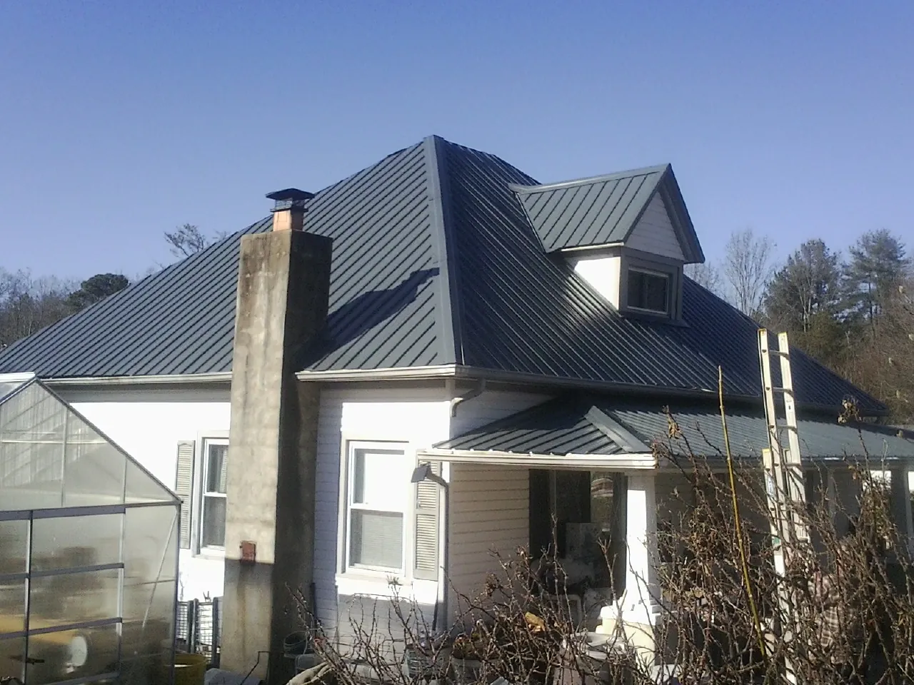 Dark blue standing seam metal roof on a white farmhouse with dormer — Slate & Tile Roof Repair by Roofing Brothers in Roslyn
