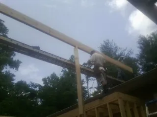 Carpenter setting a ridge beam over a new addition frame — Ice Dam Removal by Roofing Brothers in Roslyn