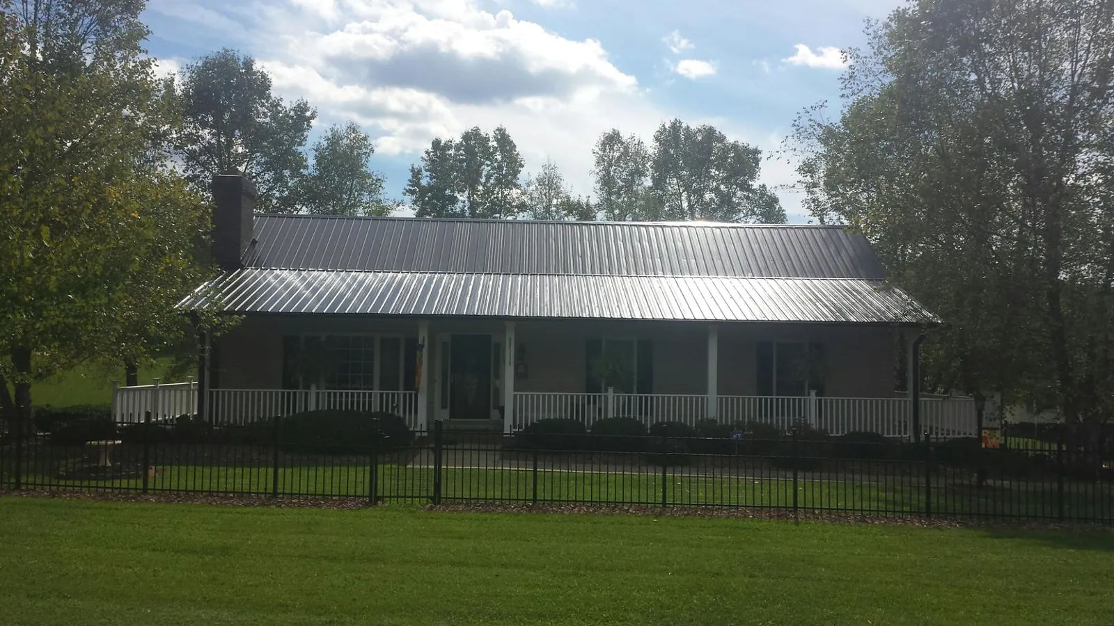 Gray metal roof on a brick ranch with a full width front porch — Gutter Guard Installation work by our crew in Roslyn