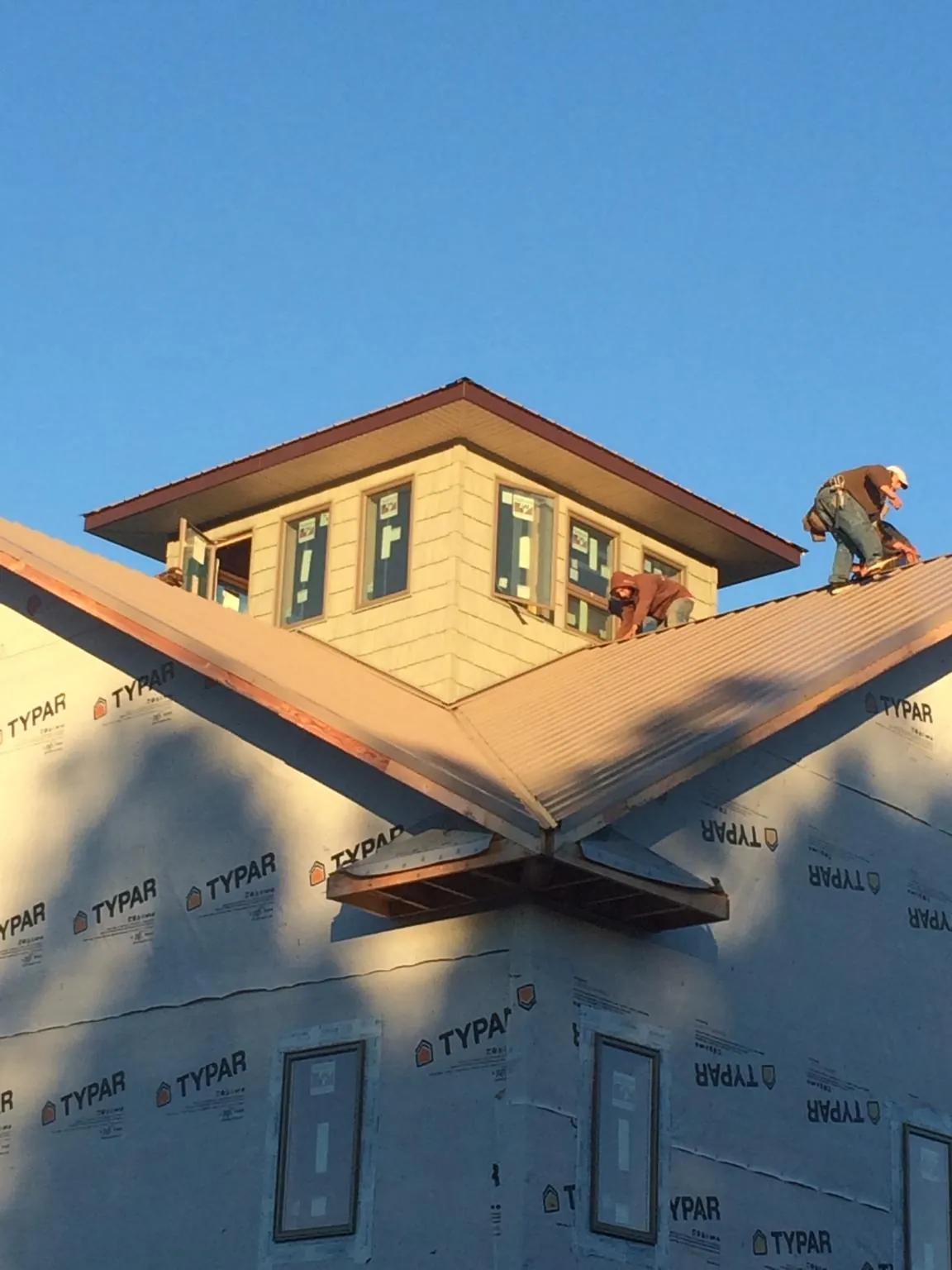 Roofers working around a rooftop cupola on a new metal roof at sunset — Roof Waterproofing in Roslyn by Roofing Brothers